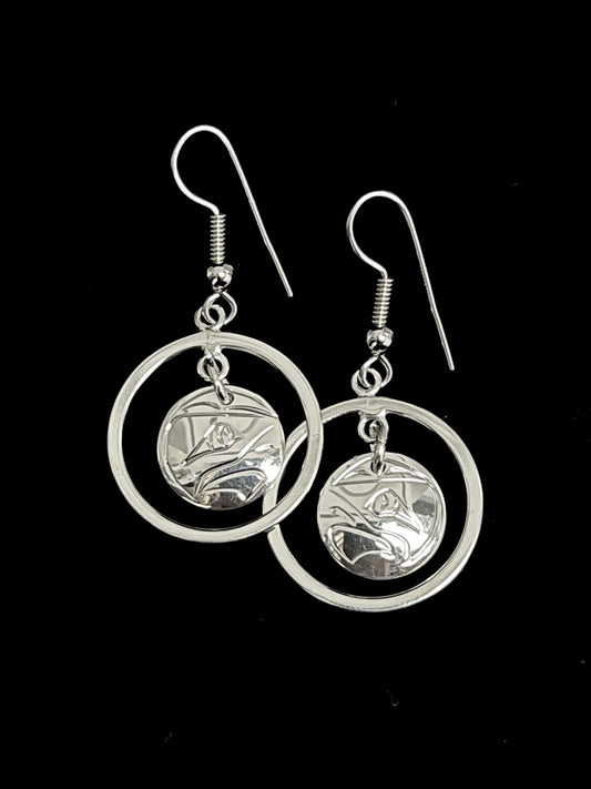 Silver circular earrings with intricate eagle designs on a black background