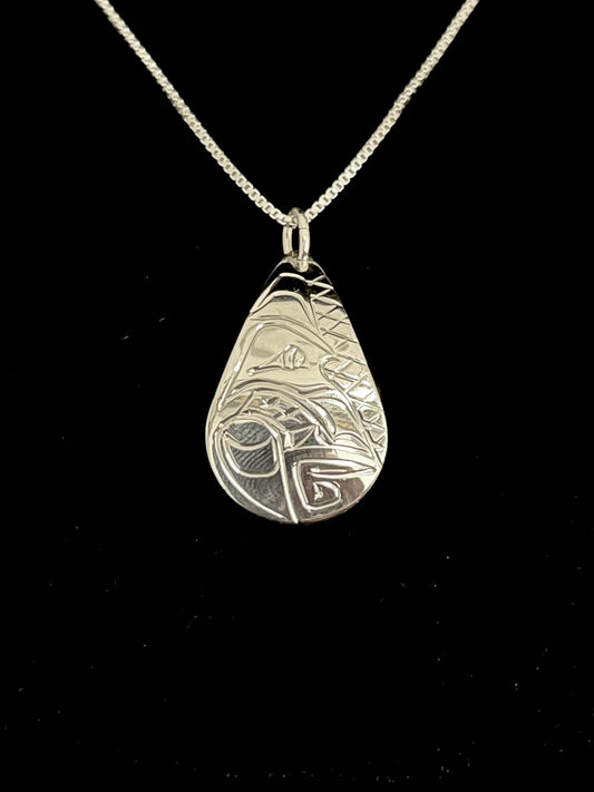 Silver pendant with intricate wolf design on a black background