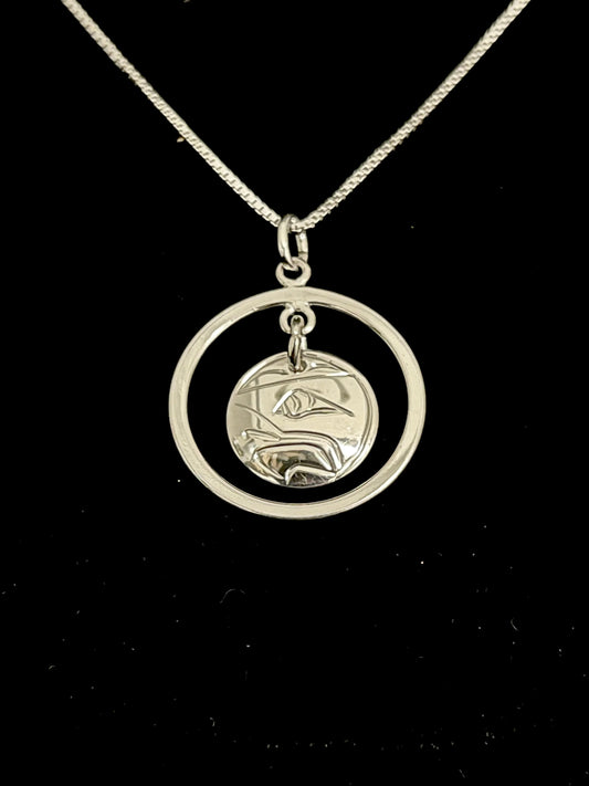 Silver necklace sliver with a circular pendant on a black background