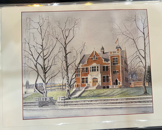 A side street image of a orange stonewall building with three tall leafless trees in the front yard, on a clear winter day.