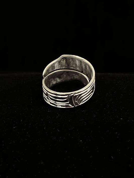 Silver ring with intricate bird design on a black background