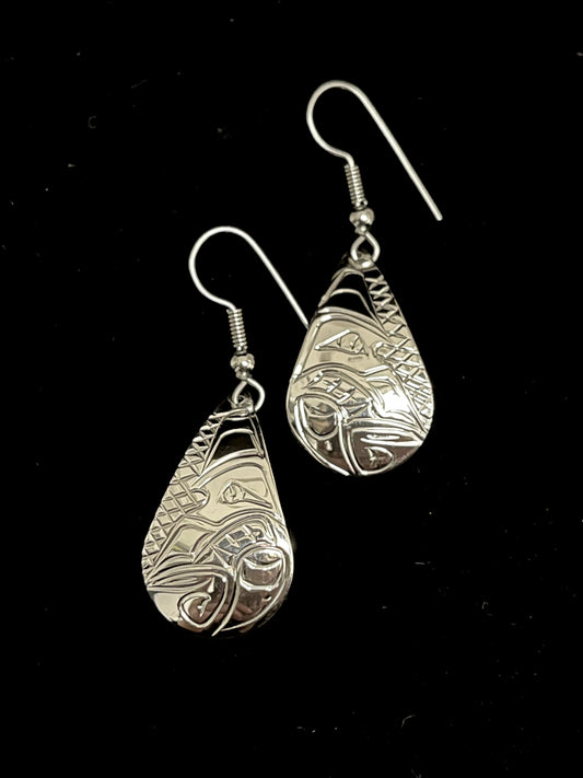 Pair of silver earrings with intricate wolf designs on a black background