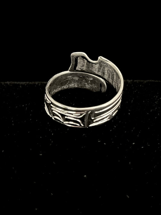 Silver ring with intricate wolf like design on a black background