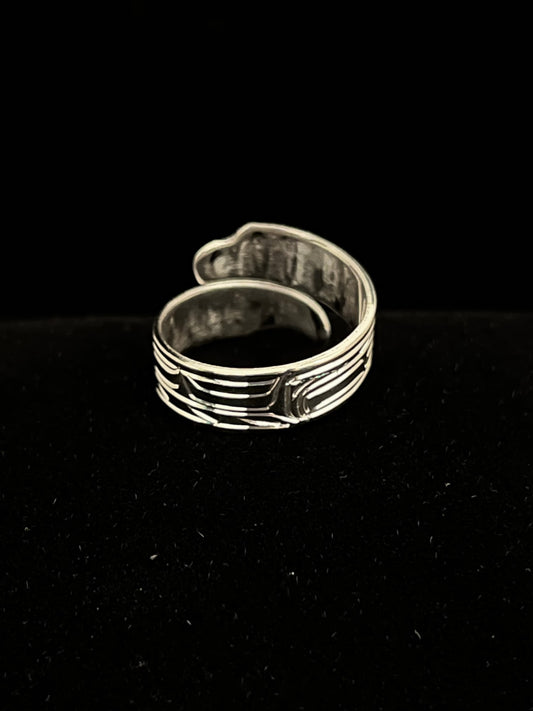 Silver ring with intricate bird design on a black background