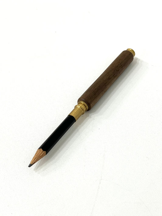 A wooden pencil with brass accents on the end, viewed from an angle against a white background.