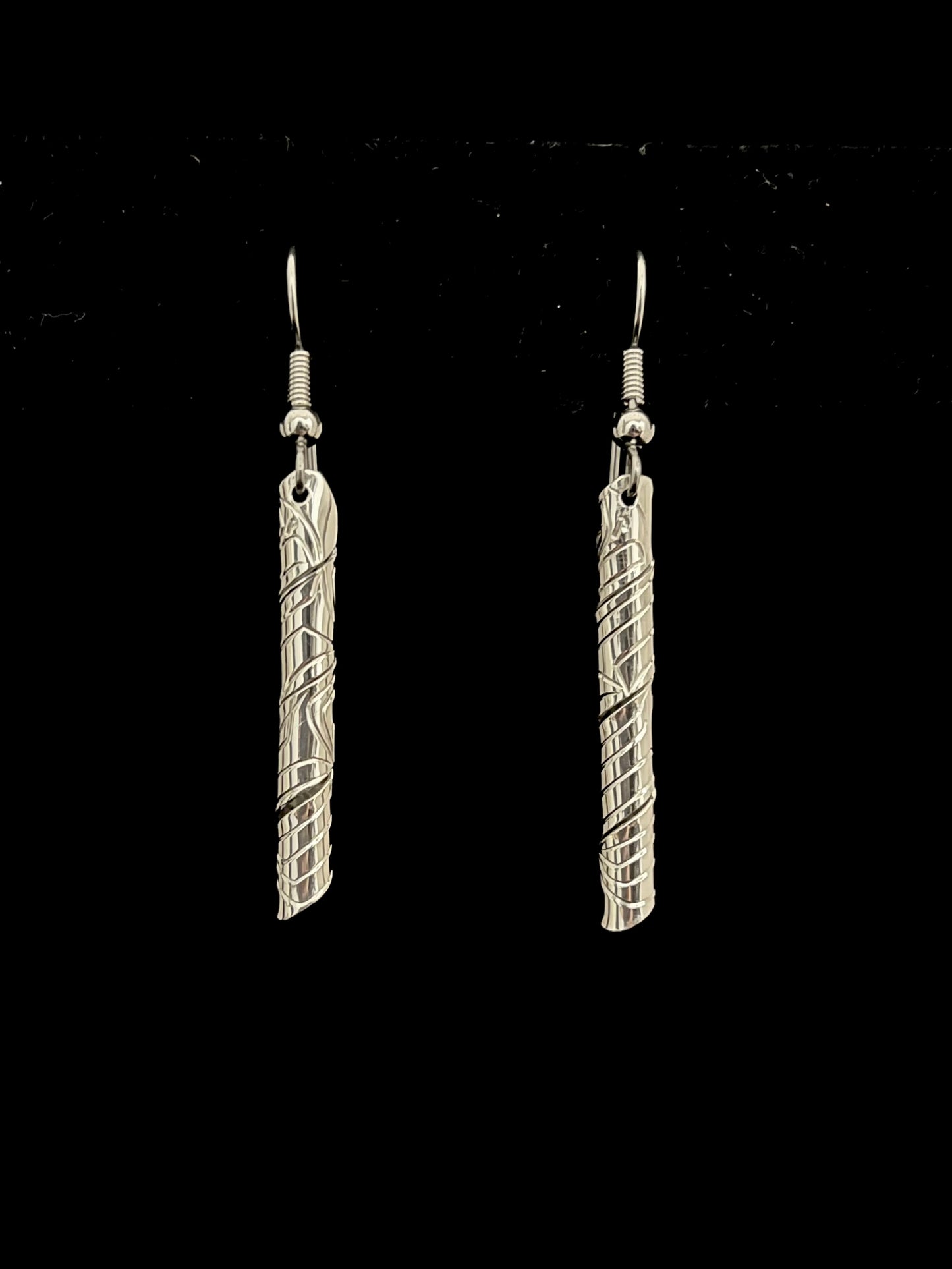 Pair of silver tube like earrings on a black background