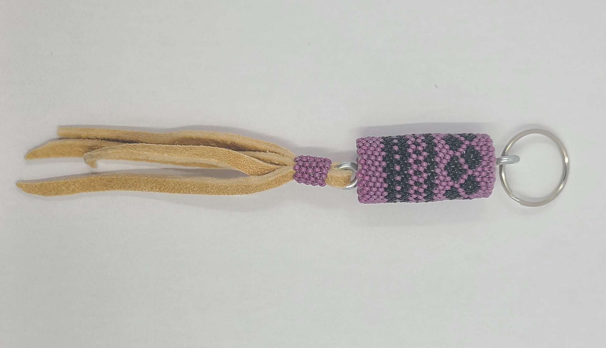 Keychain with tassel featuring a purple and black pattern on a white background