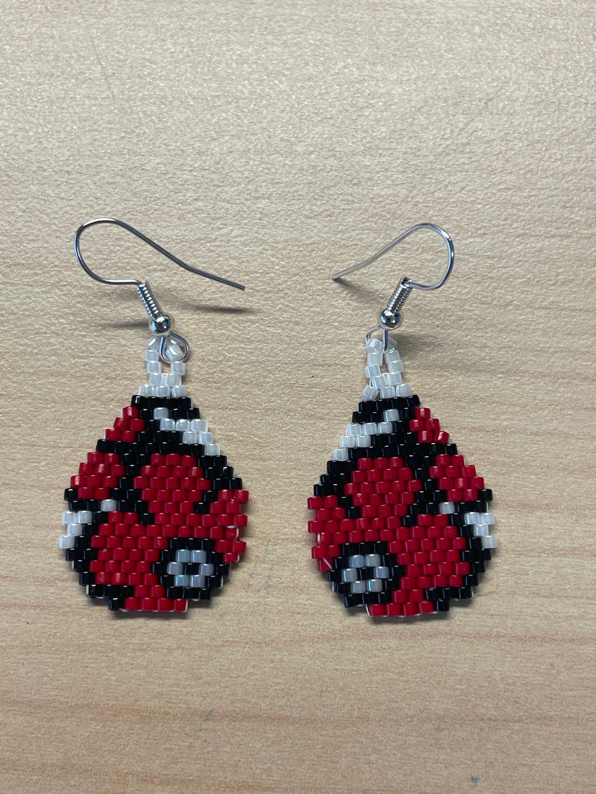Hand beaded earrings in a teardrop shape with red poppies. 