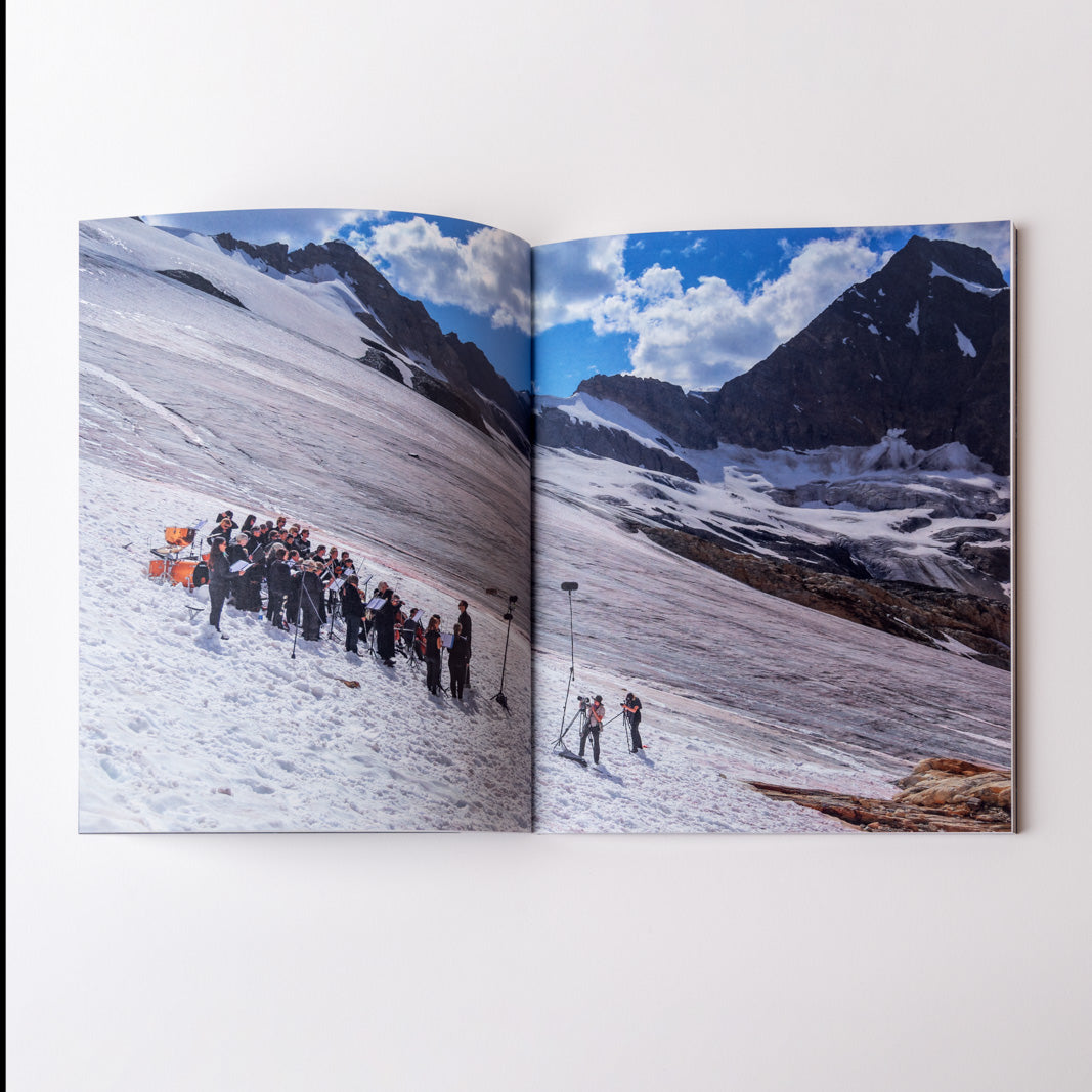Open book showing a photograph of an orchestra on a snowy mountain landscape with a glacier