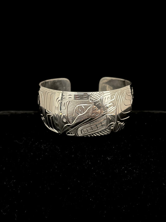 Silver bracelet with intricate wolf designs on a black background