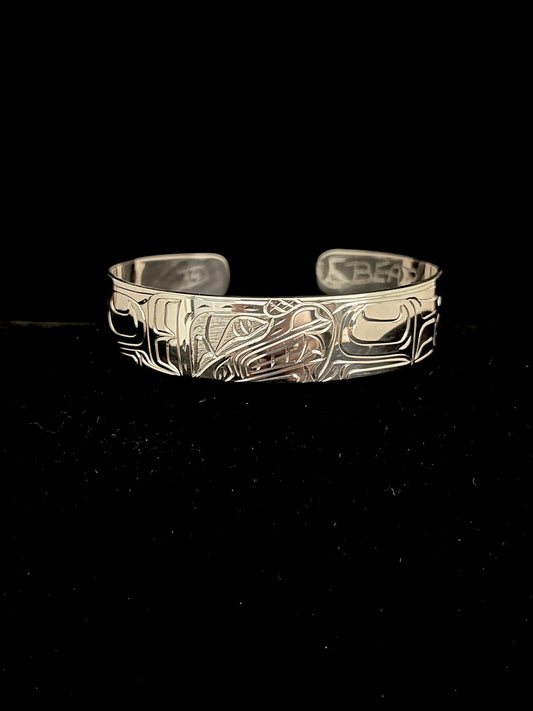 Silver bracelet with intricate bear designs on a black background