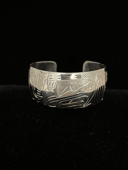 Silver bracelet with intricate eagle designs on a black background