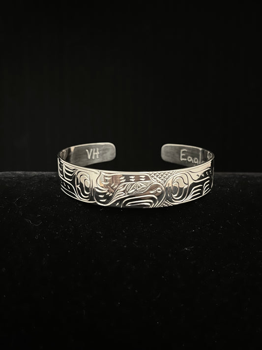 Silver bracelet with intricate eagle designs on a black background