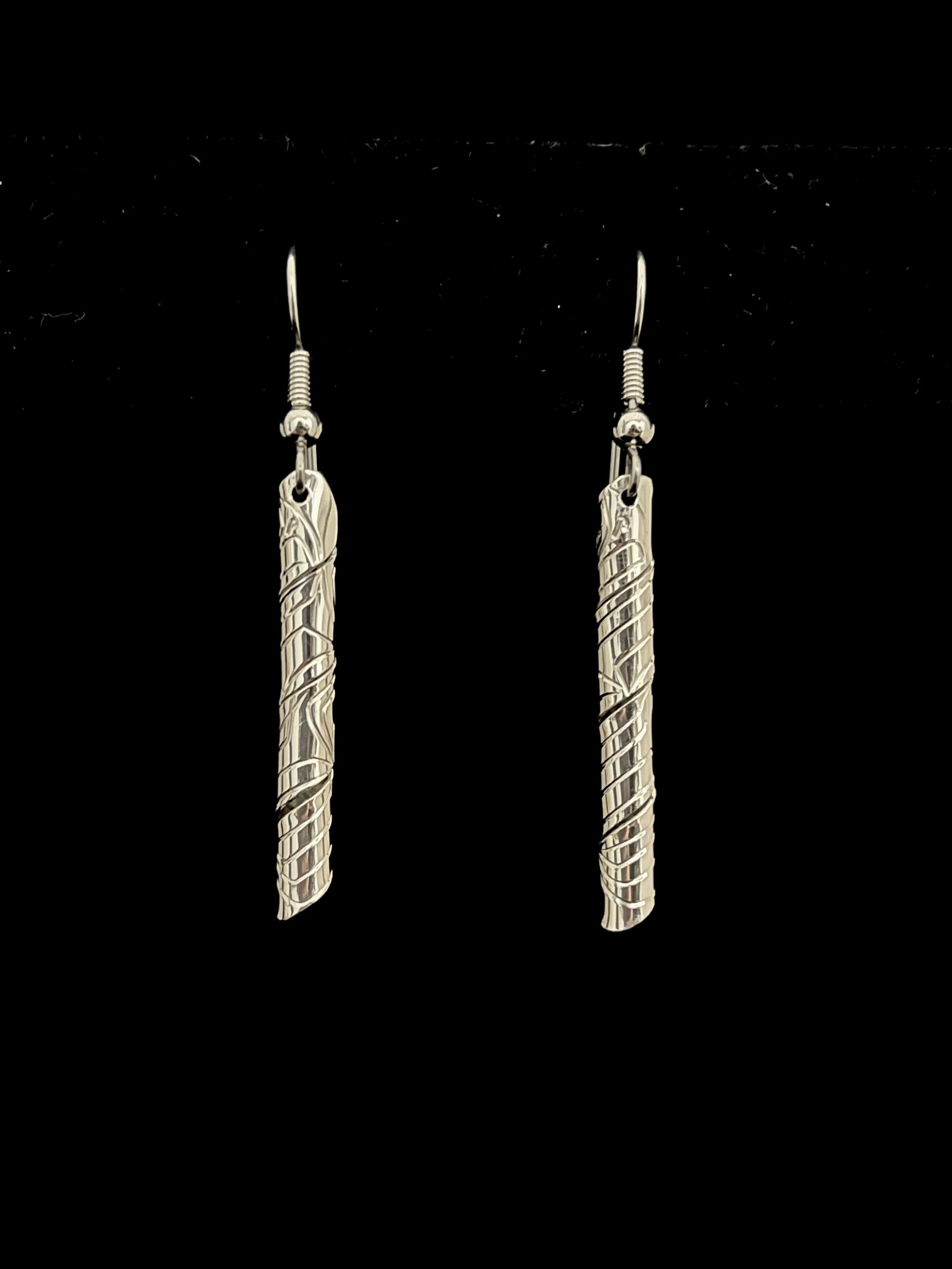 Pair of silver tube like earrings on a black background